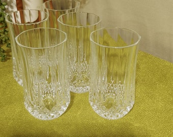 May include: Six clear glass tumblers with a diamond pattern on a green tablecloth.