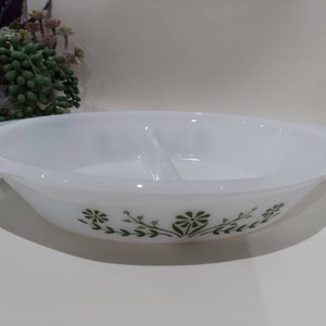May include: White divided serving dish with a green floral design. The dish has a rim and a divided center.