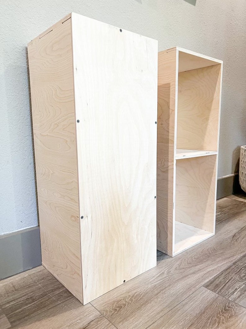 May include: Two unfinished wooden shelves, one tall and narrow, the other shorter and wider, both made of plywood.