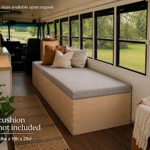 Könnte beinhalten: Eine maßgefertigte Holzbank mit grauem Kissen in einem umgebauten Bus. Die Bank ist 147 cm breit, 46 cm hoch und 74 cm tief. Dekorative Kissen in verschiedenen Farben liegen auf der Bank. Der Text "cushion not included" ist sichtbar.