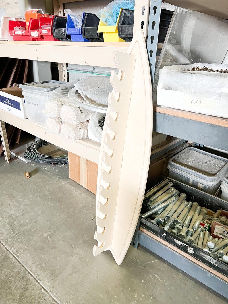 May include: A white wooden shelf unit with multiple slots for storage. The shelf is curved and has a rounded edge. The shelf is empty and ready to be used.