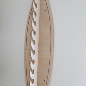 May include: A wooden surfboard wall mount with a white background and 10 cut-out hooks for hanging items.