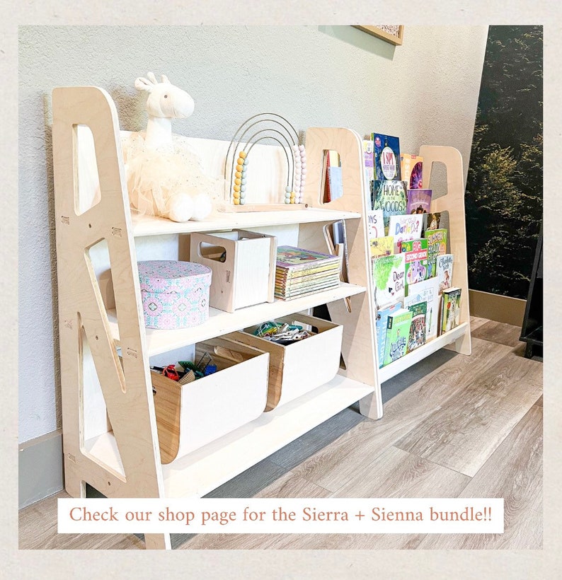May include: A light-colored wooden bookshelf with multiple shelves. The shelves hold books, toys, and storage bins. A white llama plush toy and a rainbow abacus are on display. The bookshelf is designed for children's rooms.
