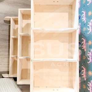 May include: A set of three wooden shelves with a natural finish. The shelves are stacked on top of each other and have a simple design. The shelves are empty and ready to be filled with items.