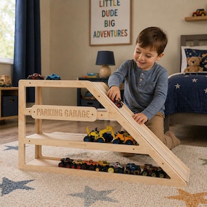 May include: A wooden parking garage toy with a ramp and multiple levels, filled with colorful toy cars. The sign reads "PARKING GARAGE". A child is playing with a red toy car on the ramp. The toy is on a star-patterned rug.