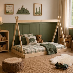 May include: A light wood teepee-style bed frame with a plaid mattress, green blanket, and bear-themed pillows. The room is decorated with framed mountain and tree art, a wooden lamp, and a stuffed bear. A small wooden toy car sits on the rug.