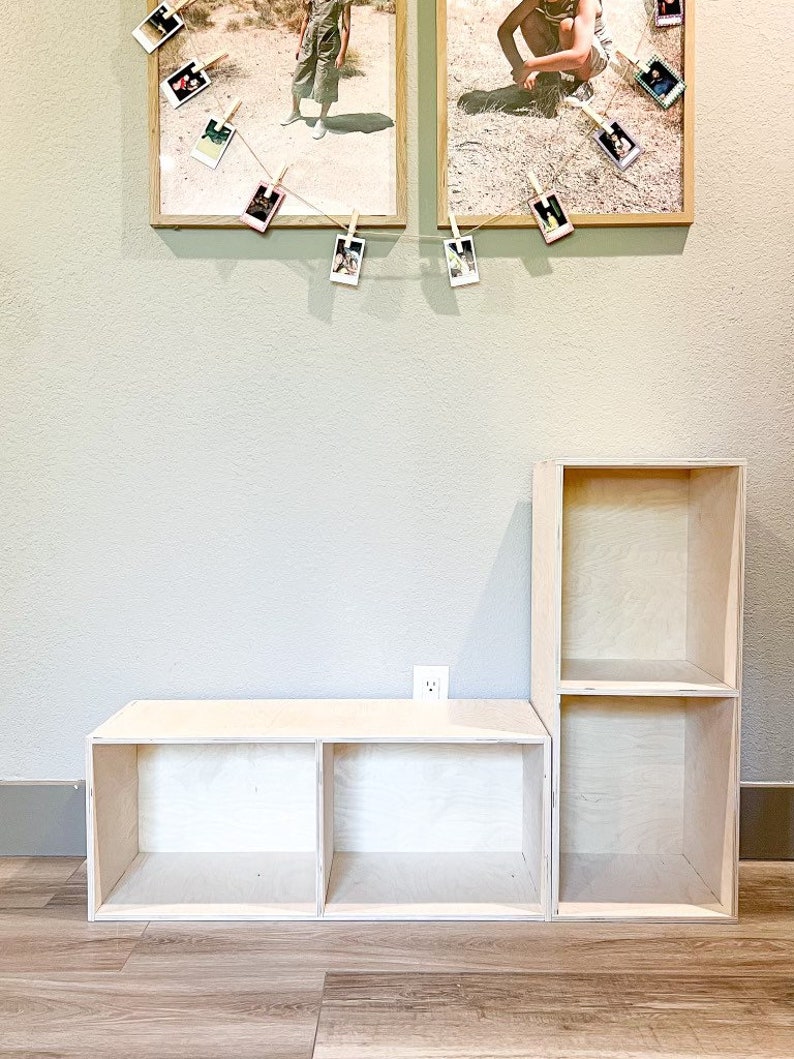 May include: A set of two unfinished wooden shelves with three compartments each. The shelves are made of plywood and have a natural wood finish. The shelves are stacked on top of each other, with the larger shelf on the bottom. The shelves are empty and ready to be decorated.