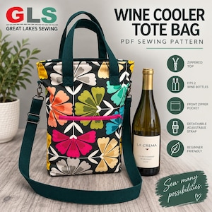 May include: A wine cooler tote bag featuring a black fabric with a colorful floral pattern, dark green handles, and an adjustable shoulder strap. The bag includes a bright pink zippered front pocket and a zippered top closure for two wine bottles.