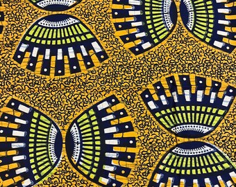 May include: A yellow fabric with a repeating pattern of blue, white and green geometric shapes. The shapes resemble stylised fans or eyes.