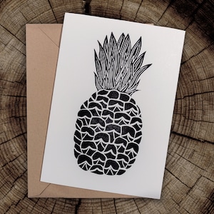 Könnte beinhalten: Eine Schwarzweißillustration einer Ananas auf einer weißen Karte. Die Ananas ist in einer einfachen, stilisierten Weise gezeichnet, wobei sowohl die Blätter als auch die Frucht aus Linien bestehen.