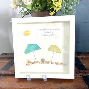 May include: White framed artwork with a quote about true friends being like sea glass. The artwork features sea glass, seashells, and a starfish.