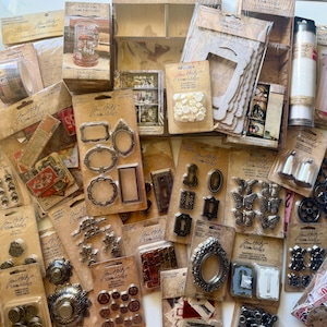 May include: A collection of Tim Holtz Idea-ology craft supplies in brown packaging, including metal frames, clock parts, decorative buttons, paper ephemera, miniature keyholes, butterfly charms, and various vintage-style embellishments for scrapbooking.