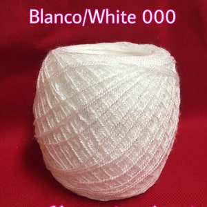 May include: A white ball of yarn with a diamond pattern. The yarn is labeled "Blanco/White 000" and "Merceria Jenni".