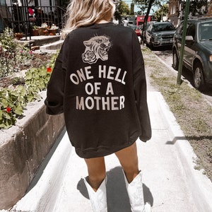 May include: Black sweatshirt with a white graphic of a snarling panther with a rose and the text "ONE HELL OF A MOTHER".
