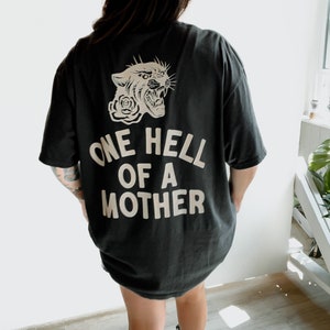 May include: Black t-shirt with a white graphic of a snarling panther with a rose and the text "One Hell of a Mother".