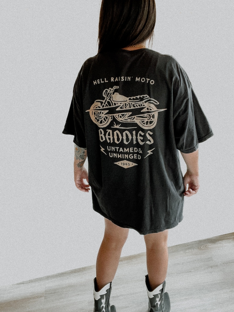 K&ouml;nnte beinhalten: Schwarzes Oversize-T-Shirt mit einem Grafikdruck eines Motorrads und dem Text "Hell Raisin' Moto Baddies Untamed & Unhinged 1945"