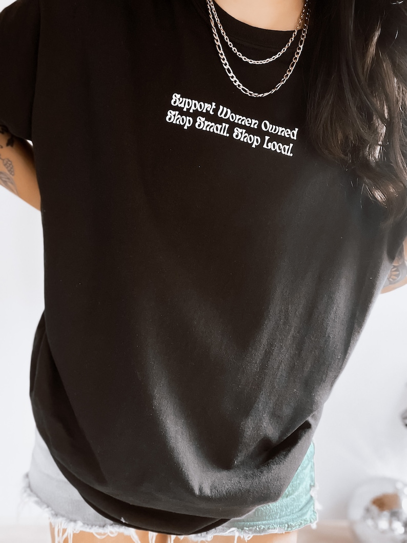May include: Black t-shirt with the text "Support Women Owned. Shop Small. Shop Local." in white lettering.