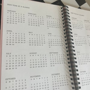 K&ouml;nnte beinhalten: Ein rosa-farbener, spiralgebundener Planer, der Jahreskalender f&uuml;r 2024 und 2025 zeigt. Die Seiten zeigen Monatskalender mit Daten und Wochentagen, n&uuml;tzlich f&uuml;r die Planung.