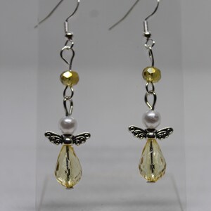 May include: A pair of silver angel dangle earrings with yellow and white beads.