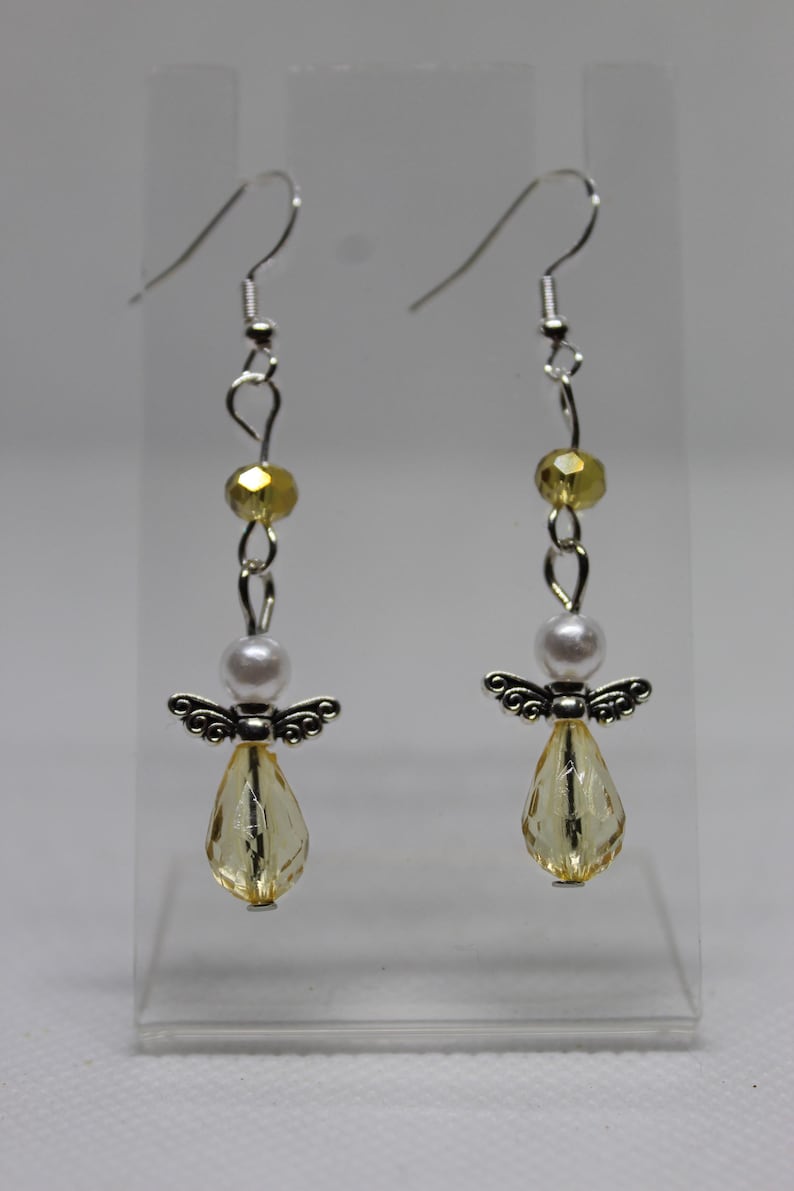 May include: A pair of silver angel dangle earrings with yellow and white beads.