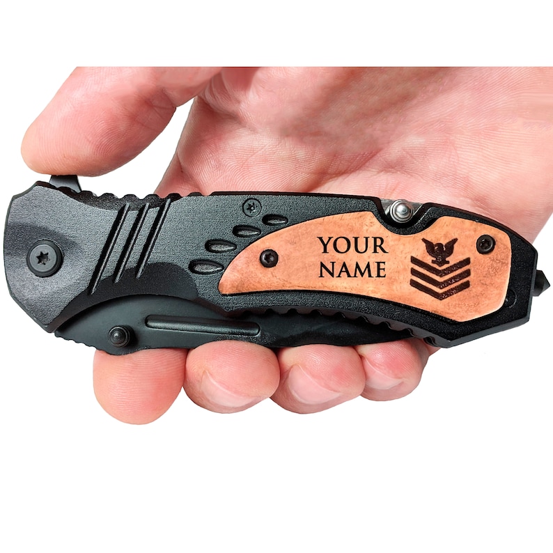 May include: Black folding pocket knife with a wood handle. The handle has a personalized inscription that reads "YOUR NAME" and a small eagle insignia.