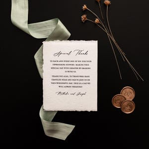 K&ouml;nnte beinhalten: Eine Hochzeitsdankeskarte mit den Worten "Special Thanks" in eleganter Schrift. Die Karte befindet sich auf strukturiertem Papier, begleitet von einem salbeigr&uuml;nen Band, Trockenblumen und Wachssiegeln, alles vor einem schwarzen Hintergrund.