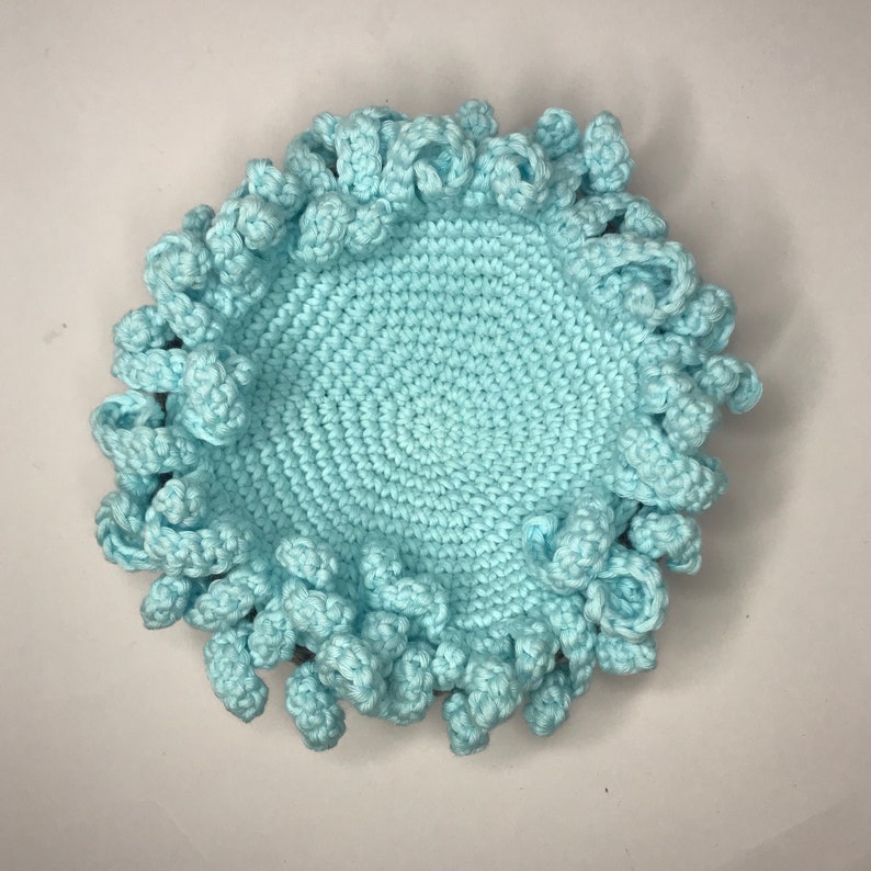 May include: A light blue crocheted bowl with a textured, ruffled edge.