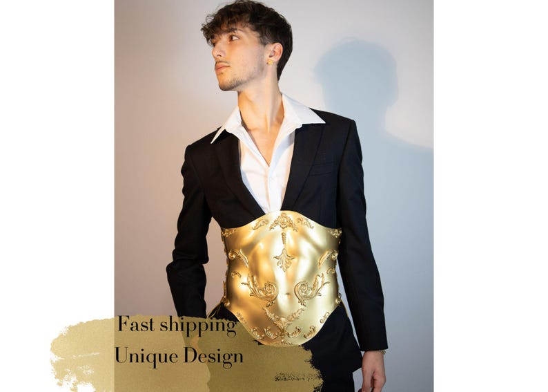 K&ouml;nnte beinhalten: Ein goldfarbenes, verziertes Kleidungsst&uuml;ck im Korsettstil mit floralem Design wird &uuml;ber einem wei&szlig;en Hemd und einer schwarzen Anzugjacke getragen. Das Bild enth&auml;lt den Text "Unique Design".