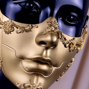 K&ouml;nnte beinhalten: Eine goldfarbene Maske f&uuml;r Maskenb&auml;lle mit aufwendigen, erhabenen floralen und scrollartigen Details. Die Maske bedeckt das untere Gesicht und weist eine modellierte Nase und Lippen auf. Die Maske wird auf einem schwarzen Schaufensterpuppenkopf pr&auml;sentiert.