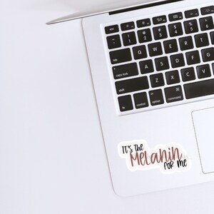May include: A white laptop with a sticker that says "It's the Melanin for me" in brown lettering on a white background.