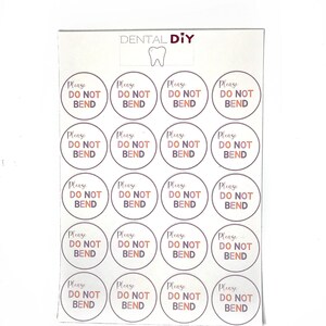 May include: A sheet of circular stickers, each bearing the text "Please Do Not Bend" in a brown font. The stickers are arranged in a grid pattern on a white background. The words "DENTAL DIY" and a tooth graphic are at the top.