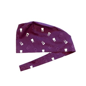 May include: Purple surgical scrub hat with a white tooth pattern.