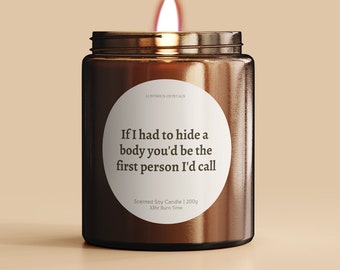 May include: A brown glass candle with a white label that reads "If I had to hide a body you'd be the first person I'd call". The label also says "Scented Soy Candle | 200g 33hr Burn Time".