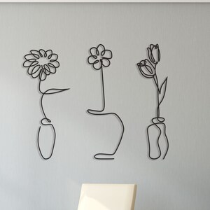 Peut inclure: Trois sculptures murales en métal noir représentant des fleurs dans des vases. Les sculptures sont de style moderne et constituent un excellent moyen d'ajouter une touche de nature à n'importe quelle pièce.