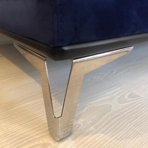 May include: Close-up of a dark blue velvet sofa with chrome legs. The legs are angled and have a modern design.