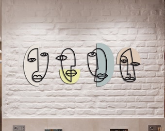 Può includere: Quattro volti astratti in linea d'arte in cornici ovali su un muro di mattoni bianchi. Le cornici sono in tonalità di rosa, giallo, blu e crema.