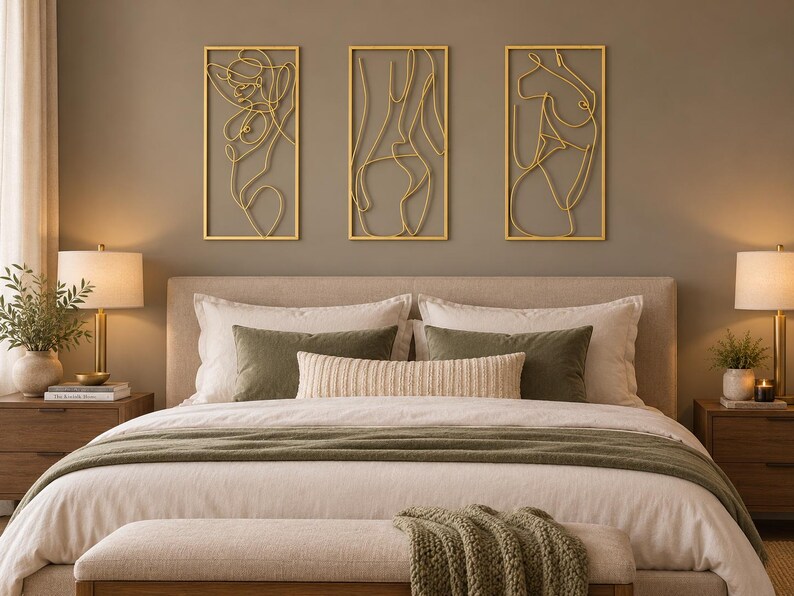 May include: Three rectangular gold-colored metal wall art pieces featuring continuous line drawings of human figures. Each piece is framed in a thin gold border and displays a stylized, abstract outline of a body in a minimalist wire design.