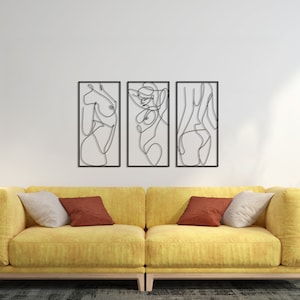 May include: A set of three rectangular wall art pieces featuring black continuous line drawings of human figures. Each piece is framed in a thin black border, showcasing abstract silhouettes of the body in a minimalist, single-line artistic style.