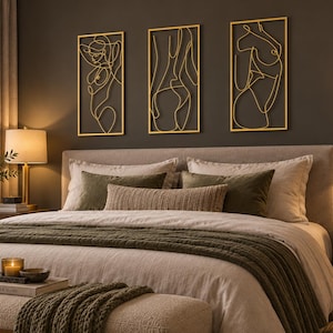 May include: A set of three rectangular gold-colored metal wall art pieces featuring continuous line drawings of human figures. Each piece is framed in a thin gold border and displays a unique abstract silhouette of a person in a minimalist style.