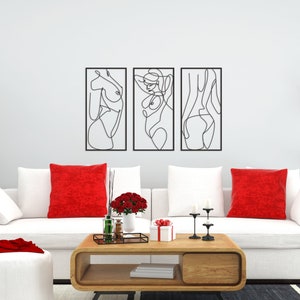 May include: A set of three rectangular black metal wall art pieces featuring continuous line drawings of human figures. Each piece is framed in a thin black border, showcasing abstract silhouettes of the body in a minimalist black wire design.