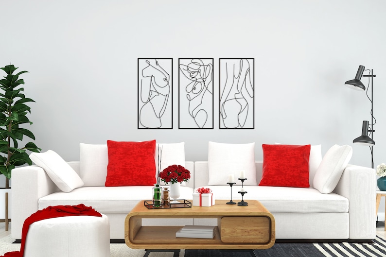 May include: A set of three rectangular black metal wall art pieces featuring continuous line drawings of human figures. Each piece is framed in a thin black border, showcasing abstract silhouettes of the body in a minimalist black wire design.