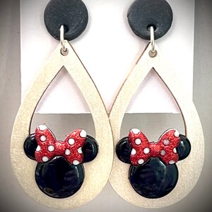 May include: A pair of dangle earrings with a wooden teardrop shape and a black and red Minnie Mouse head design. The earrings have black clay tops.