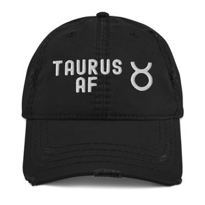Könnte beinhalten: Schwarze, abgenutzte Baseballkappe mit weißer Stickerei, die "Taurus AF" und ein Stier-Sternzeichen zeigt.