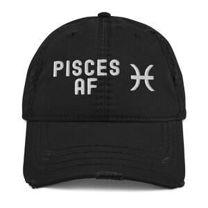 Könnte beinhalten: Schwarze, abgenutzte Baseballkappe mit weißer Stickerei, die "Pisces AF" und ein Fische-Sternzeichen zeigt.