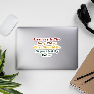 May include: A sticker with the text "Laundry is the only thing that should be separated by color" in a retro font with red, orange, yellow, and green colors.
