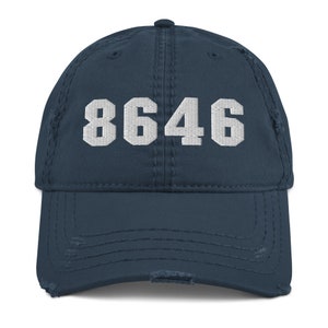 May include: A navy blue distressed baseball cap with the number 8646 embroidered in white on the front.