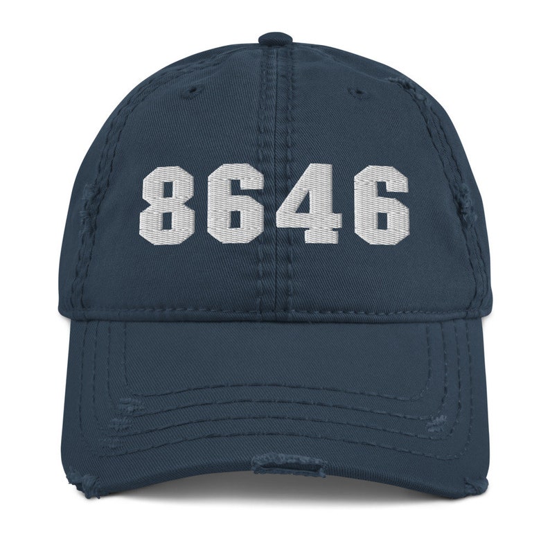 May include: A navy blue distressed baseball cap with the number 8646 embroidered in white on the front.
