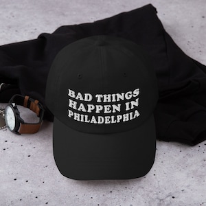 May include: Black baseball cap with white embroidered text that reads "Bad Things Happen in Philadelphia".