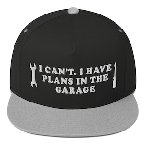 Puede incluir: Gorra de béisbol negra y gris con un diseño bordado en blanco que dice "No puedo. Tengo planes en el garaje." con una llave inglesa y un destornillador gráfico a cada lado del texto.