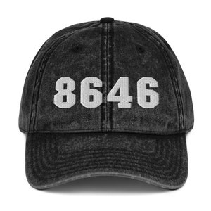 May include: Black vintage baseball cap with the number 8646 embroidered in white on the front.